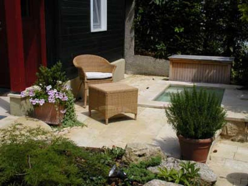 Erholung pur: windgeschützter, sonniger Sitzplatz auf Sandsteinterrasse, kleiner Pool mit plätscherndem Wasser, duftender Rosmarin im Terracottatopf.